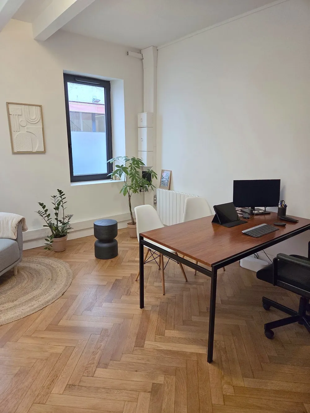 Les bureaux de 2XL Invest à Lyon : table de travail en bois, chaises pour les clients, plantes et coin fauteuil sur parquet en point de Hongrie